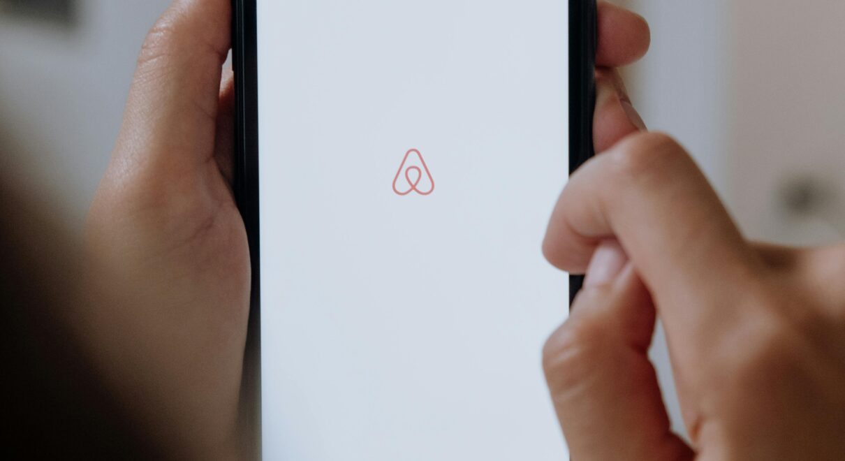 Person holding smartphone with Airbnb app logo on screen